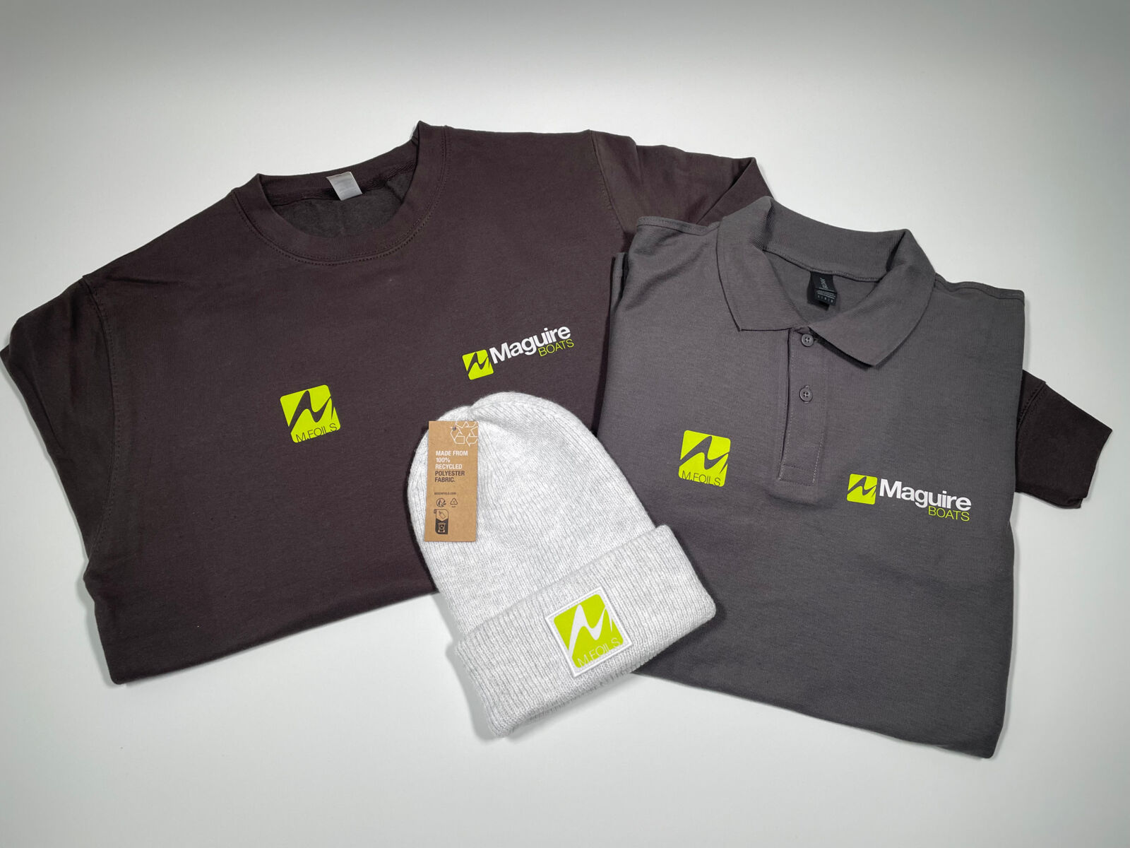 Dark grey custom clothing for customer with green and silver logo on sweatshirt, polo shirt and beanie