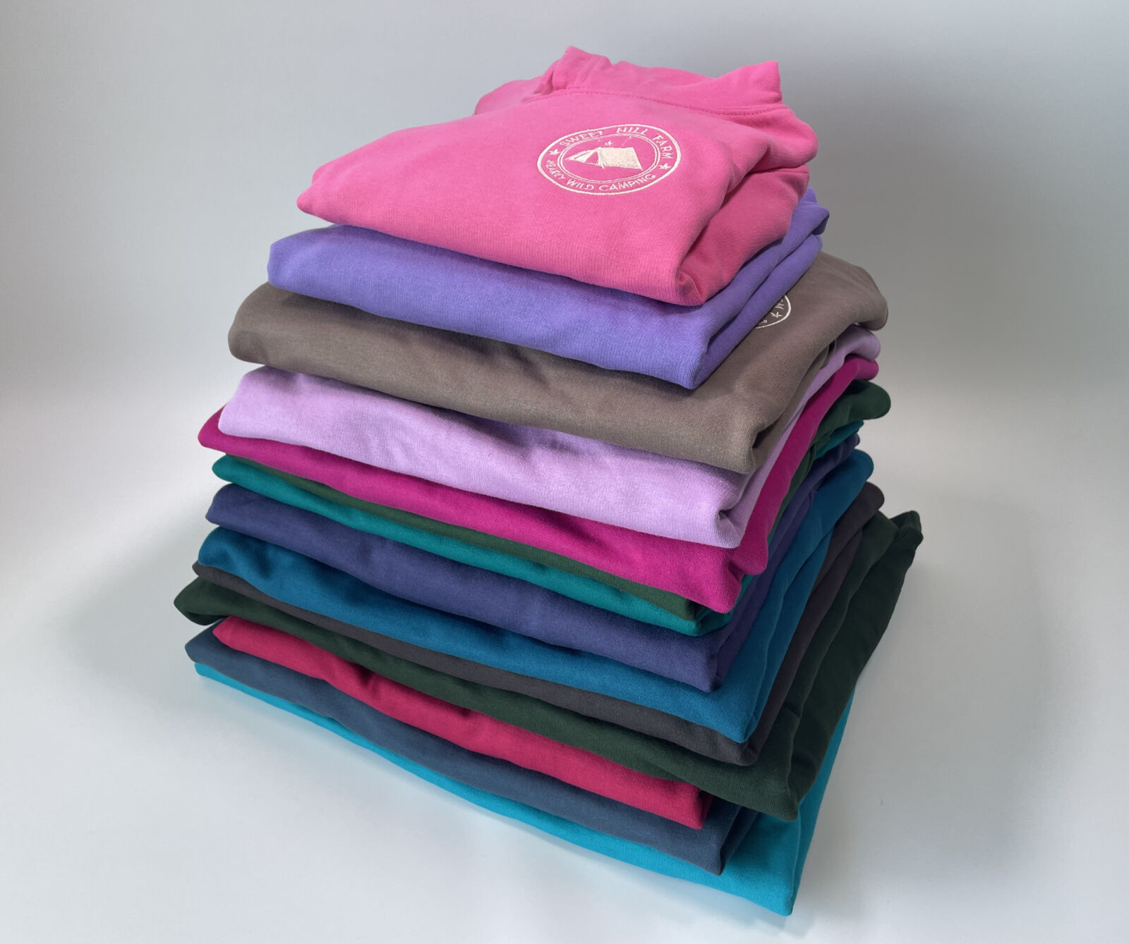 Stack of brightly coloured hoodies with embroidery