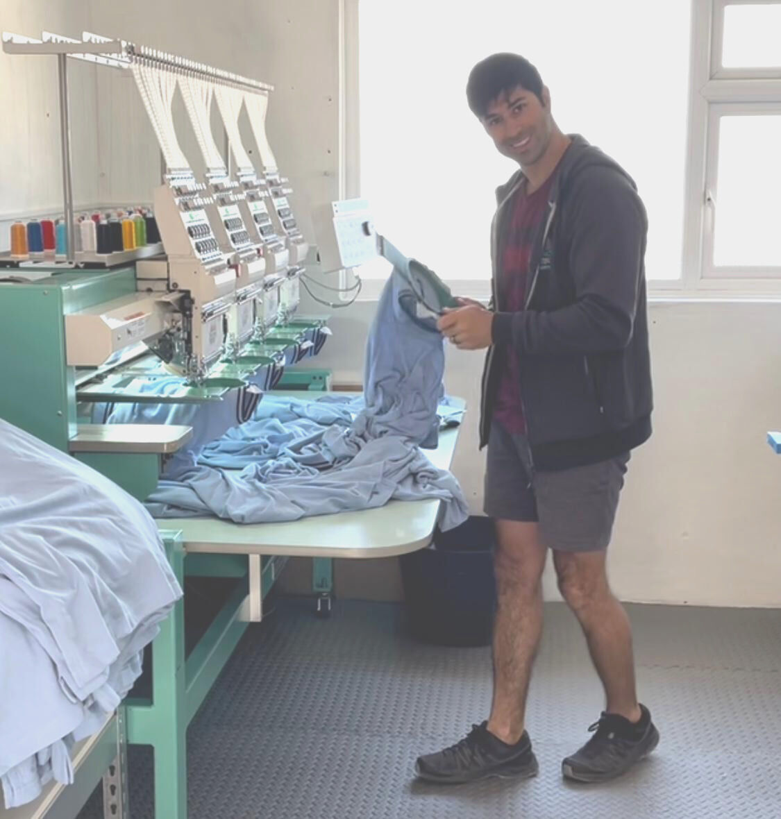 Kyle working at the embroidery machine with light blue tops